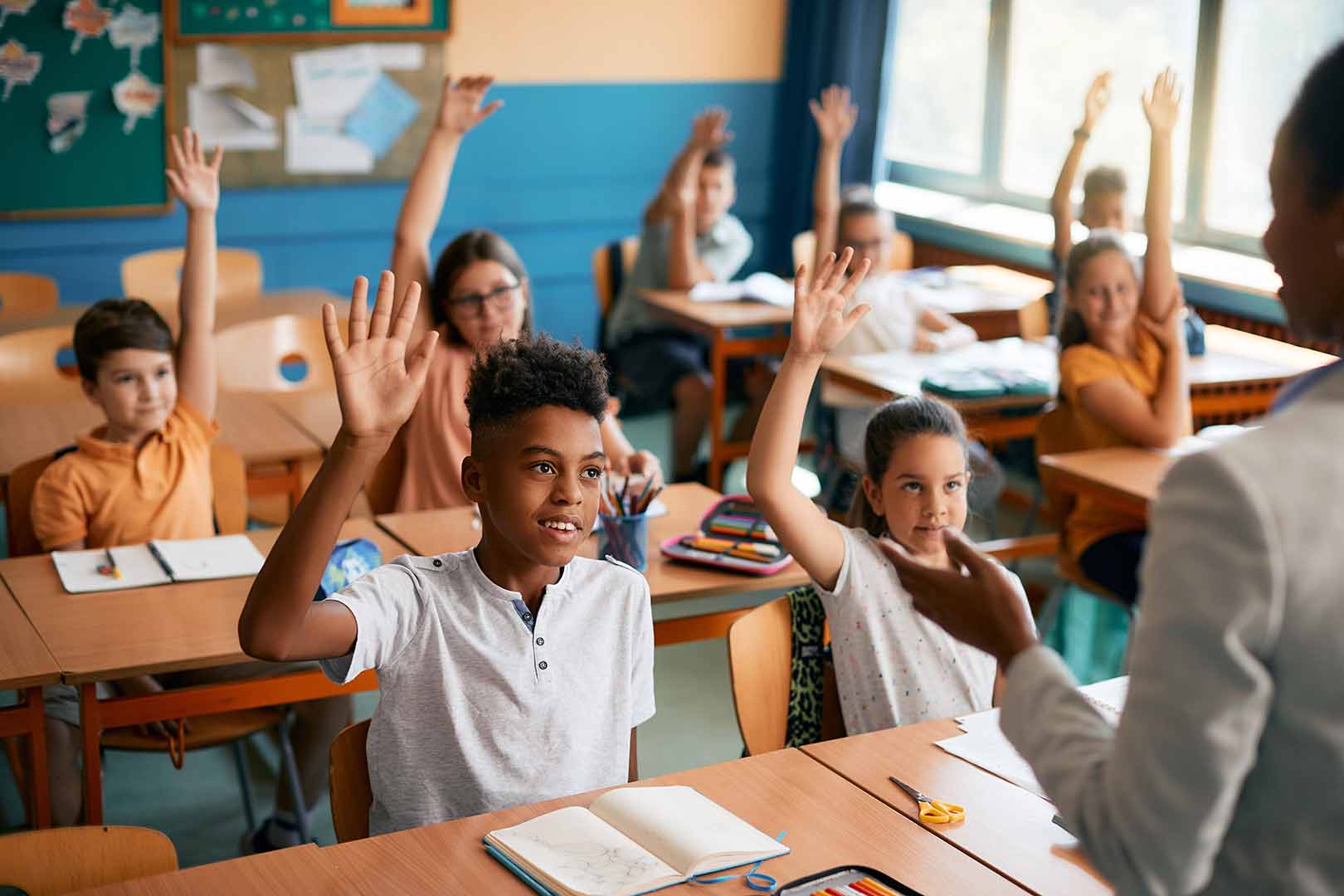 Group of students raising their hands during class