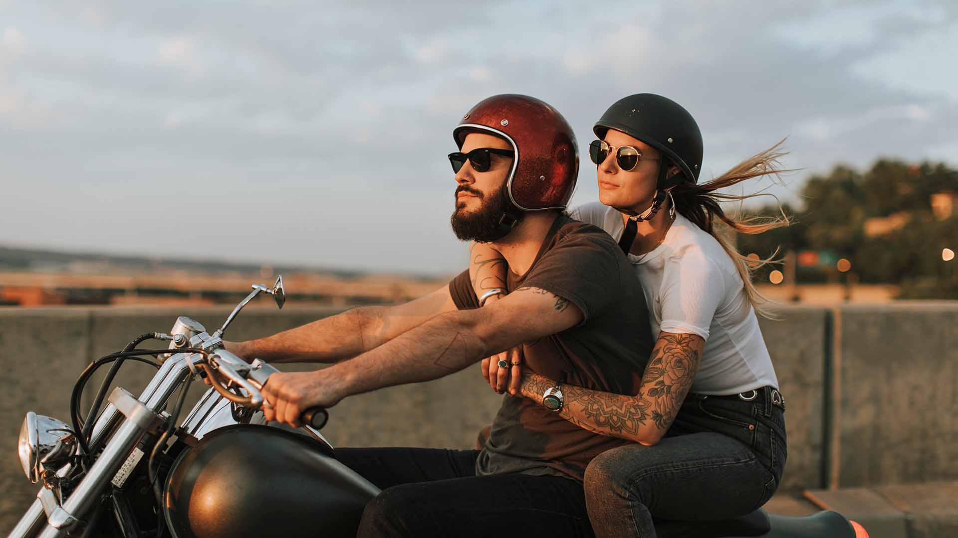 Couple on motorcycle riding down the road in the sunset