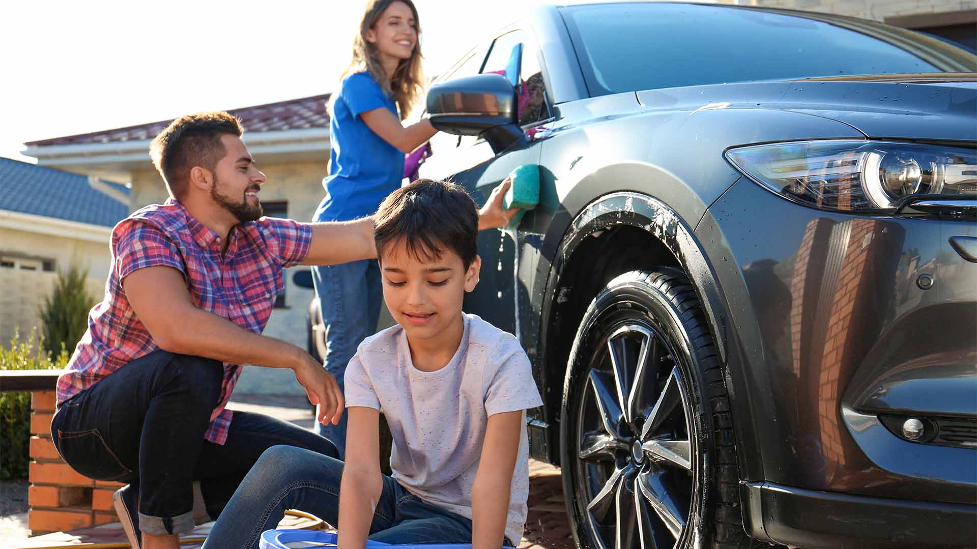 Family washing car together in driveway