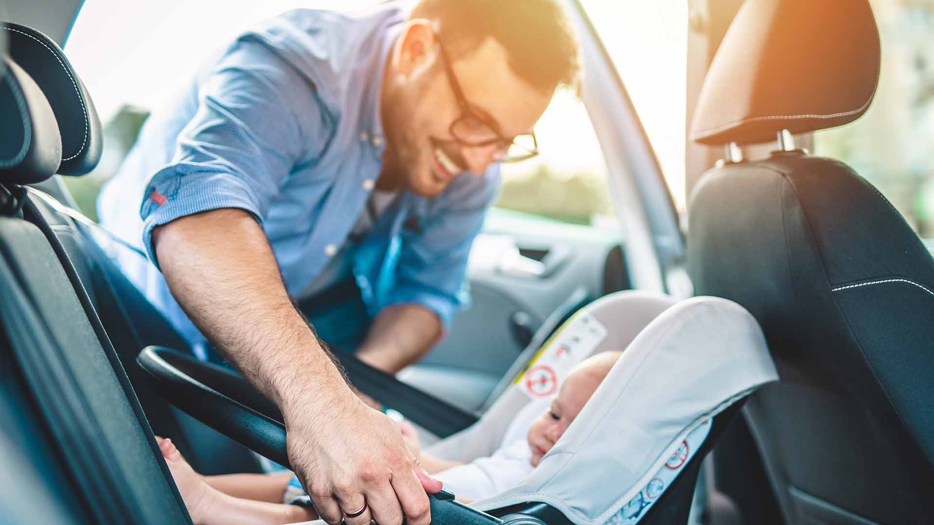 Father placing baby in car seat
