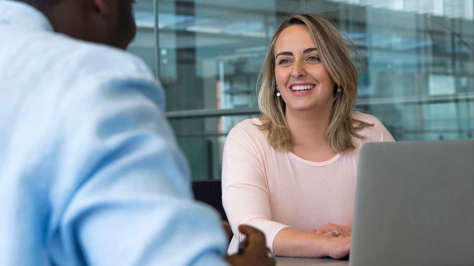 smiling woman with laptop listens to friend talk