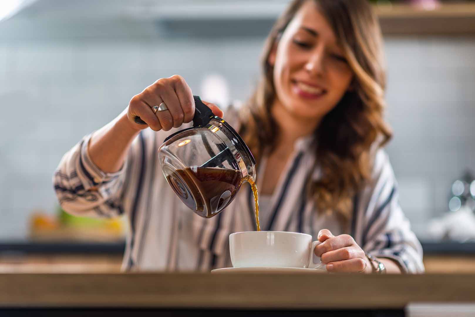 Woman pouring cup of coffee at home